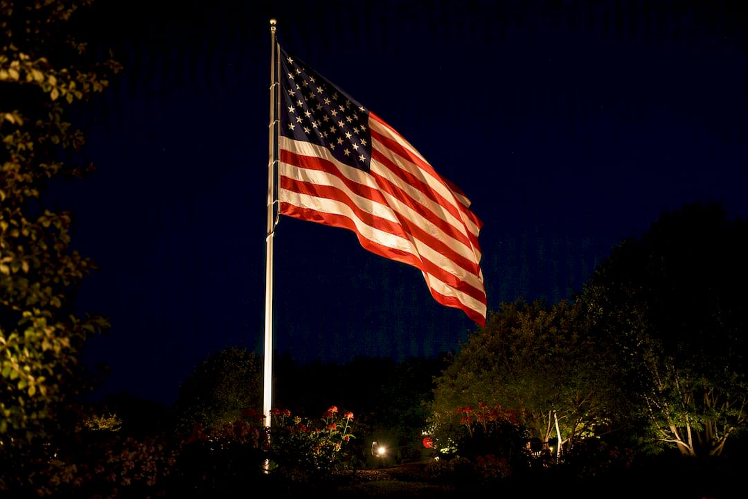 American flag illuminated by uplights at night