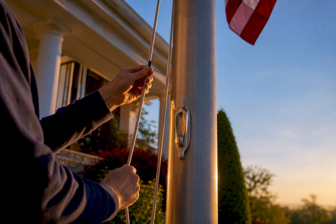 Hands raising a flag at sunrise