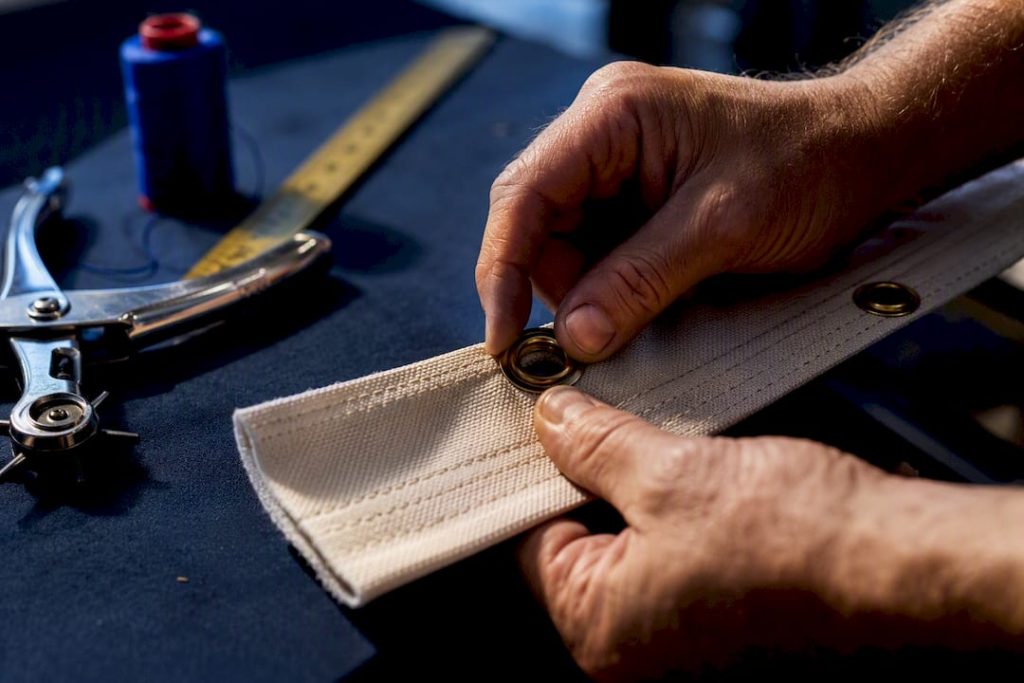 Hands installing grommet in reinforced flag header