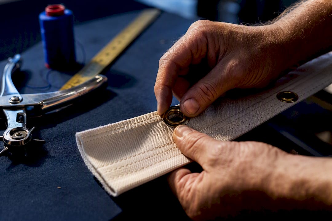 Hands installing grommet in reinforced flag header